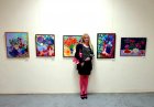 Artist - Elena Gontarenko against the background of his paintings.