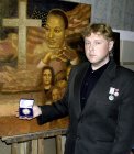 Alexey Akindinov with the awards – three medals of the Winner: the Gold medal \"SAINT MICHAEL\", the Silver medal «Russian Gallery the XXI-st century» and a medal «Talent and Calling» the World Alliance \"Peacemaker\" against his picture \"Martin Luther K